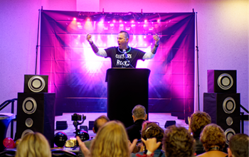 a man giving a presentation with large speakers