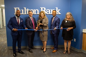 5 people standing and cutting a large ribbon