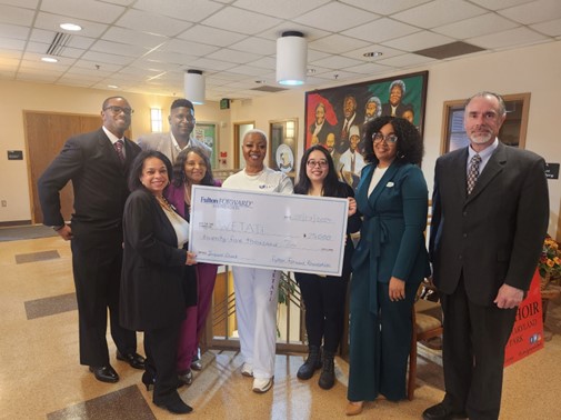 Fulton Bank employees present members of the Wetati academy with a $25,000 check